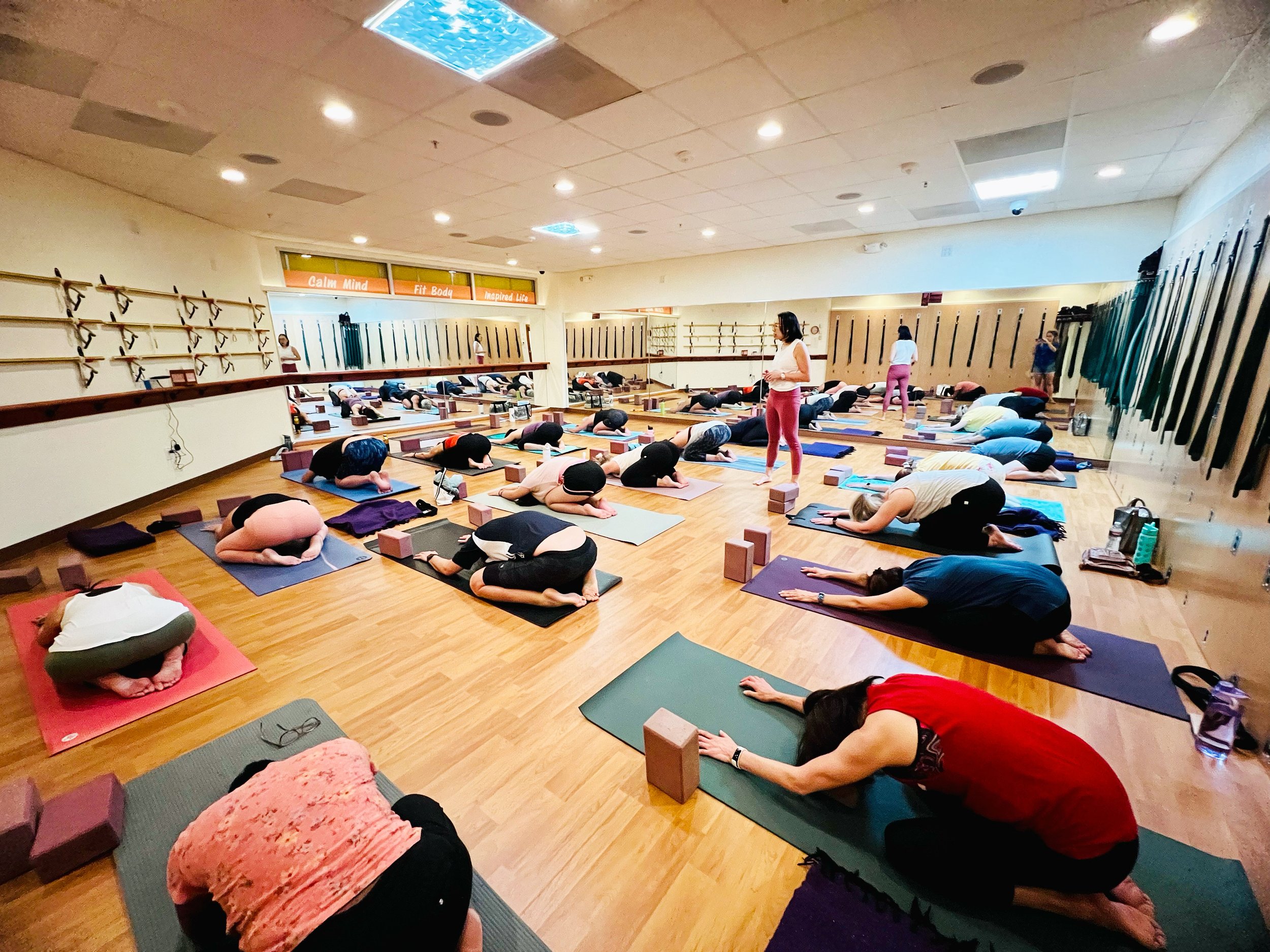 A teacher guiding a group in resting yoga poses at Yoga Health Center